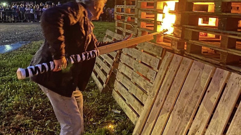 Fivemiletown District Orange Lodge shared the images of Charlie Lawson setting the Roughan bonfire alight and posing in front of it 