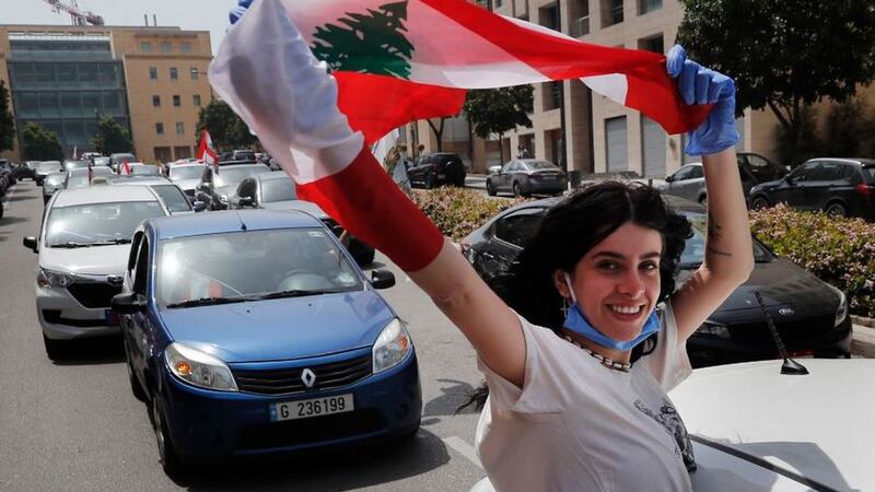 &nbsp;An anti-government protester waves a Lebanese flag as others in their cars wear masks to help curb the spread of the coronavirus, as they protest by driving their cars through the streets to express rejection of the political leadership they blame for the economic and financial crisis, in Beirut, Lebanon, today. Picture by Hussein Malla, AP