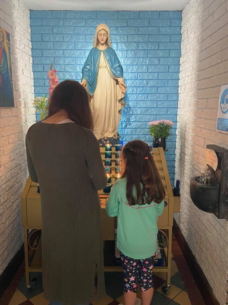 Leancha Smith lighting a candle with her daughter Meabh in St John's Church on the Falls Road.