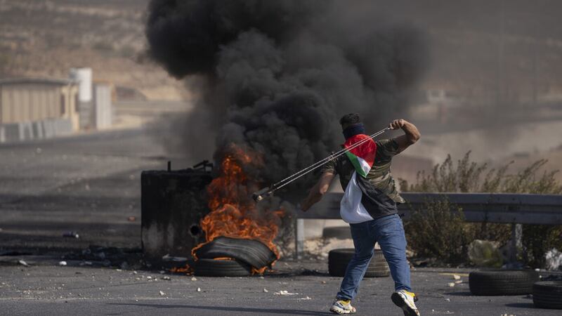 A Palestinian protester uses a slingshot during clashes with Israeli army troops in the West Bank city of Ramallah, Thursday, Oct. 20, 2022. Palestinians launched a general strike on Thursday throughout the West Bank and east Jerusalem in response to the death of a suspected Palestinian attacker. (AP Photo/Nasser Nasser)