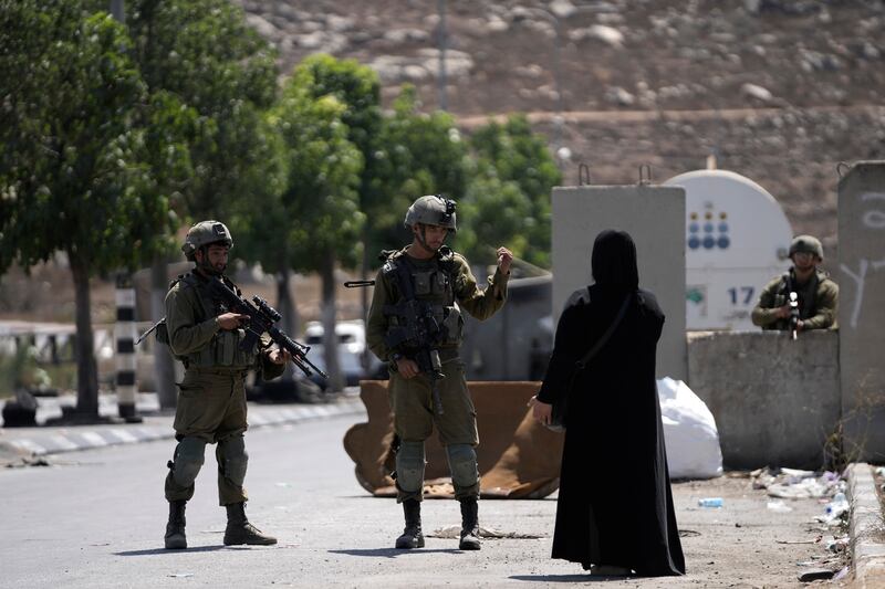 Israeli soldiers speak to a Palestinian woman near Beit Hagai, a Jewish settlement in the hills south of the Palestinian city of Hebron (Mahmoud Illean/AP)