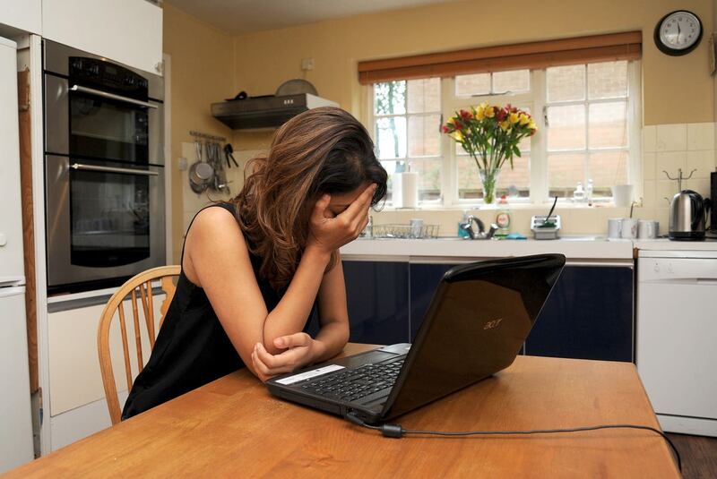 Woman looks distressed at laptop