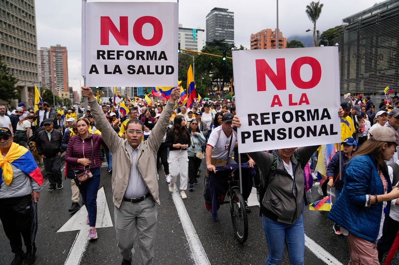Demonstrators holding signs reading in Spanish ‘No to the Health Reform’, left, and ‘No to the Pension Reform’ march to protest economic and social reforms (AP Photo/Fernando Vergara)