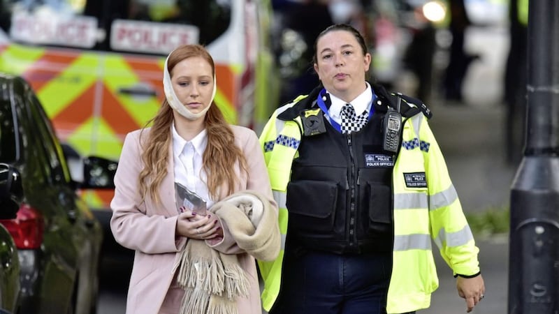 An injured woman is assisted by a police officer close to Parsons Green station in west London after an explosion on a packed London Underground train PICTURE: Dominic Lipinski/PA 