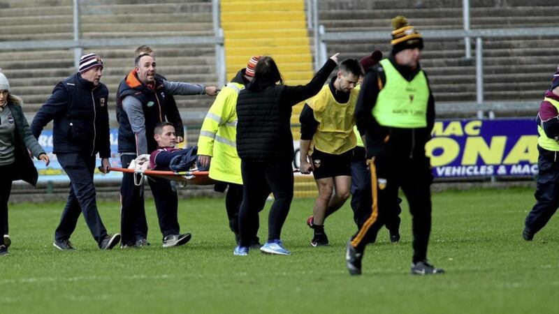 Arron Graffin is carried from the Armagh Athletic Grounds pitch by, among others, Ballycran sub and GP, Andy Bell. Picture by Seamus Loughran 