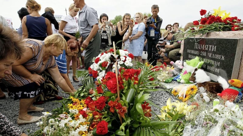 Residents lay flowers to commemorate victims of the Malaysian Airlines plane, near the village of Hrabove, Donetsk region, eastern Ukraine, yesterday. Relatives and friends of people killed three years ago when a surface-to-air missile blew a Malaysia Airlines passenger jet out of the sky over Ukraine gathered to mark the anniversary at a new memorial near the Amsterdam airport from which the plane departed PICTURE: Olexander Ermochenko/AP 