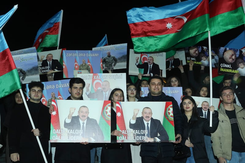 People hold national flags and posters with portraits of Azerbaijan’s President Ilhan Aliyev after the presidential election in Baku, Azerbaijan this week (AP)