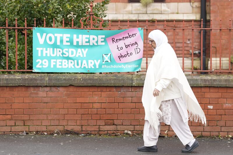 A woman walks past a sign for a polling station location in Rochdale, Greater Manchester, ahead of the by-election
