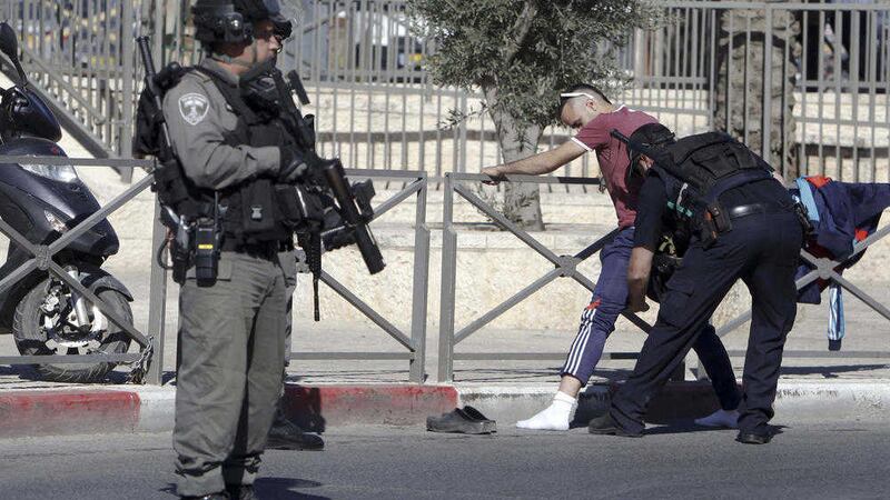 An Israeli policeman searches a Palestinian near the scene of an attack in Jerusalem on Friday