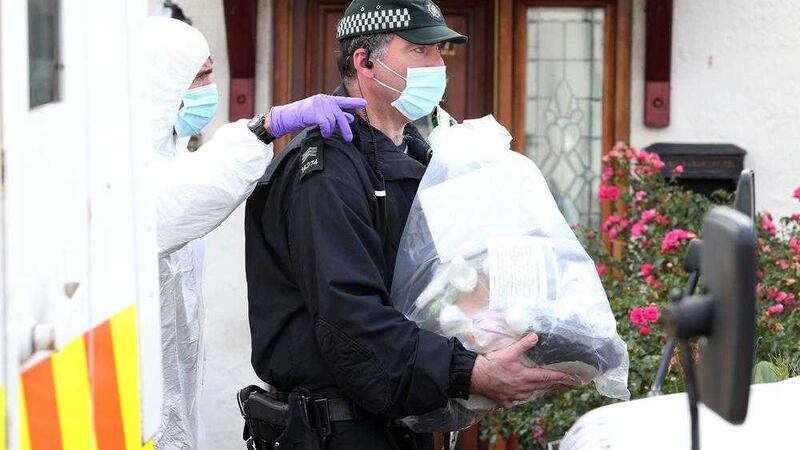Police forensic officers remove items from a house in the Ballymurphy area following a poice operation. Picture Mal McCann. 