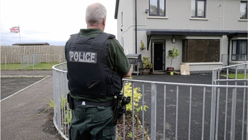 Police guard a boarded up home in Ballysillan Avenue after residents flee following terror attacks. Picture by Hugh Russell. 