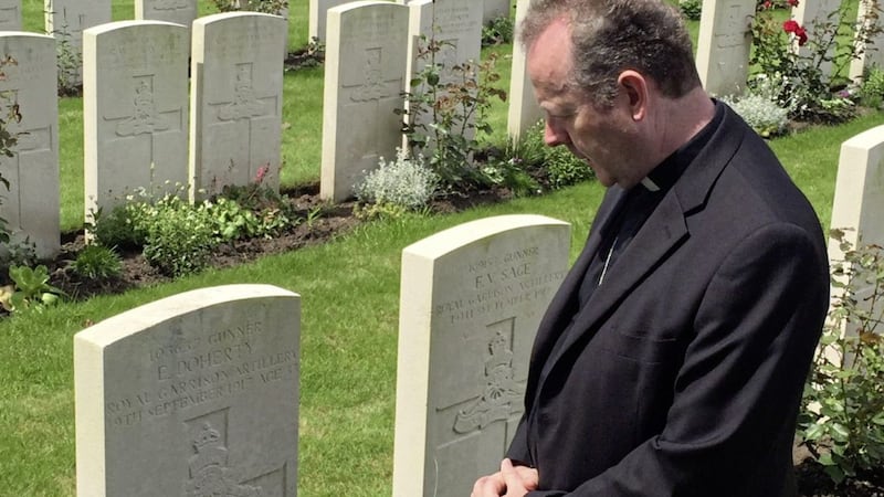 Archbishop Eamon Martin kneeling in prayer at Edward Doherty&#39;s headstone at Canada Farm Cemetery, about five miles outside Ypres, Belgium. The headstone reads: &quot;Gunner E Doherty, Royal Garrison Artillery, 19th September 1917, aged 33.&quot; 