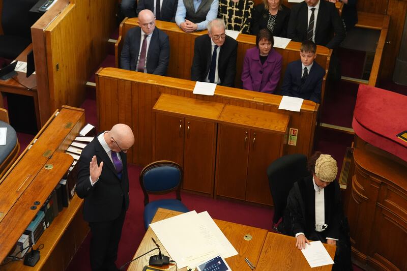 John Swinney, left, took the oath while his family watched on