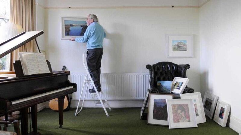 The late Joseph McWilliams begins hanging pictures for a Christmas group exibition at his gallery/home in north Belfast some years ago Picture by Mark marlow 