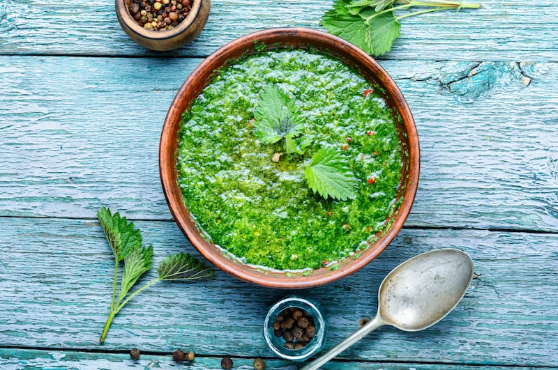 Nettle soup in bowl on wooden surface