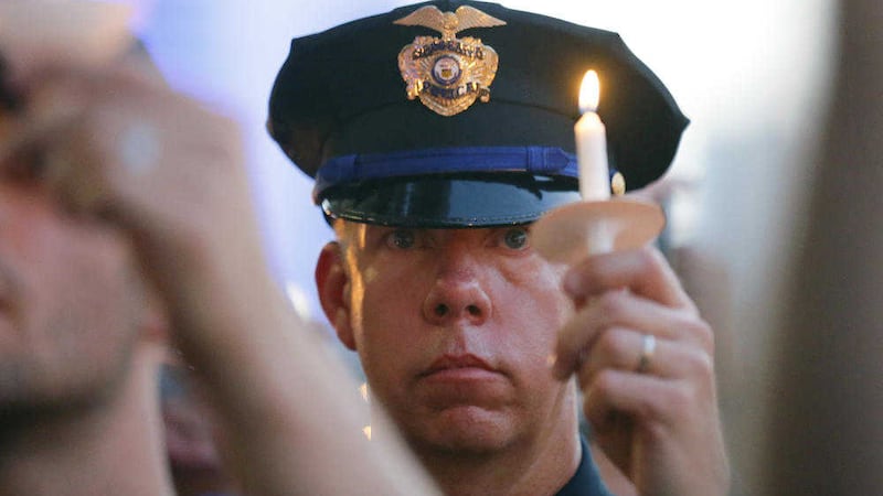 A police officer takes part in a candle-light vigil at City Hall in Dallas. Picture by Tony Gutierrez, Associated Press