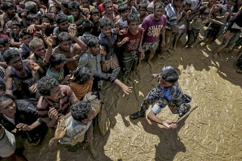 A security officer attempts to control Rohingya refugees waiting to receive aid in Cox&#39;s Bazar. Picture by Cathal McNaughton 