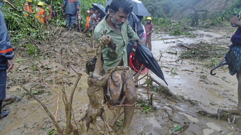 A man carries the carcass of a goat as rescuers search amid the mud after a landslide in Bandarban, Bangladesh Picture: AP 
