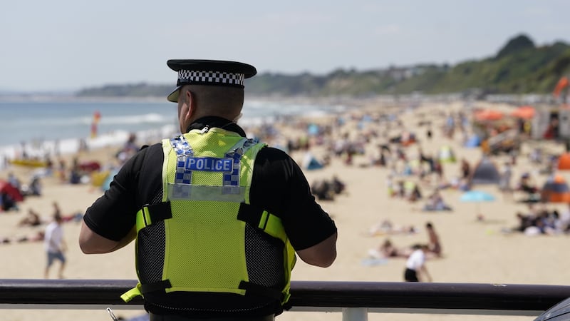 A police officer looks out over Bournemouth beach, after Joe Abbess, 17, and Sunnah Khan, 12, drowned and eight other people were treated by paramedics after they were suspected to have been caught in a riptide next to the pier at the Dorset seaside resort (Andrew Matthews/PA)