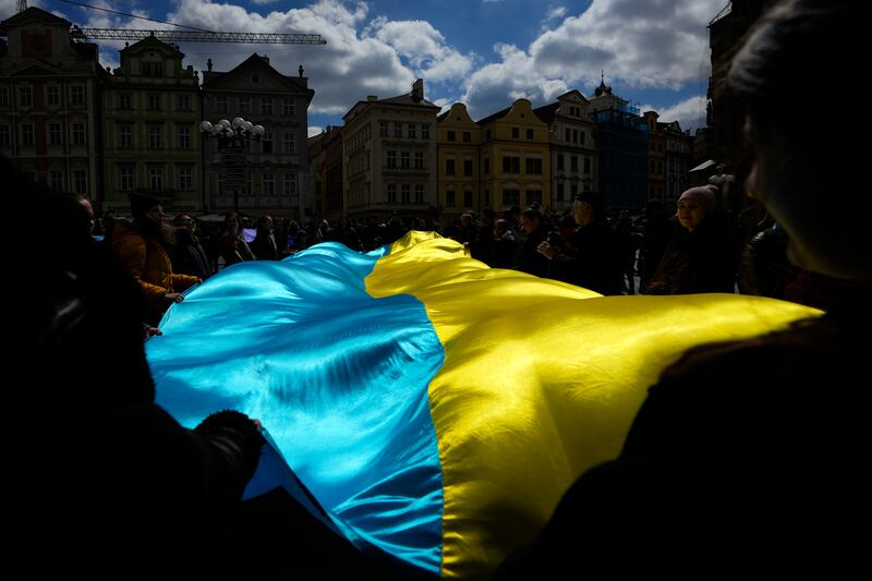People wave a Ukrainian flag during a demonstration in support of the Estonian military strategic plan for Ukraine in Prague (AP)