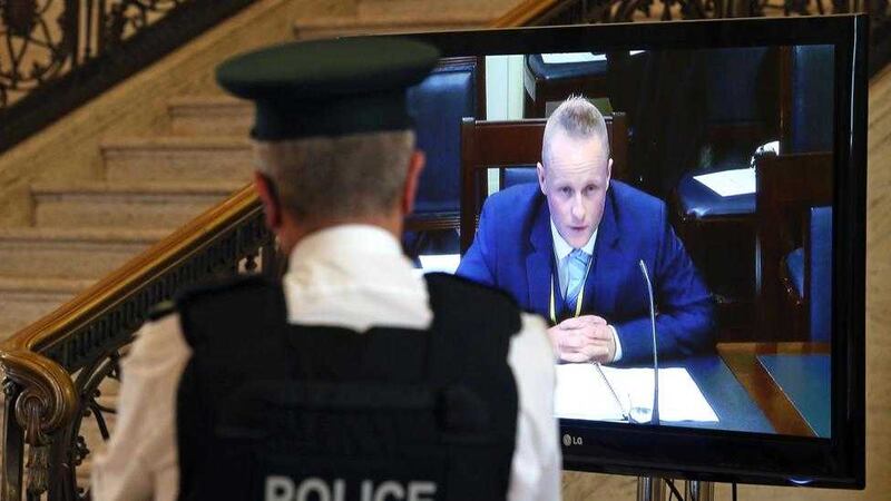 A PSNI officer watches on a tv screen in the Great Hall in Stormont as Jamie Bryson appears before the Stormont finance committee&#39;s Nama inquiry last September. Picture by Mal McCann. 