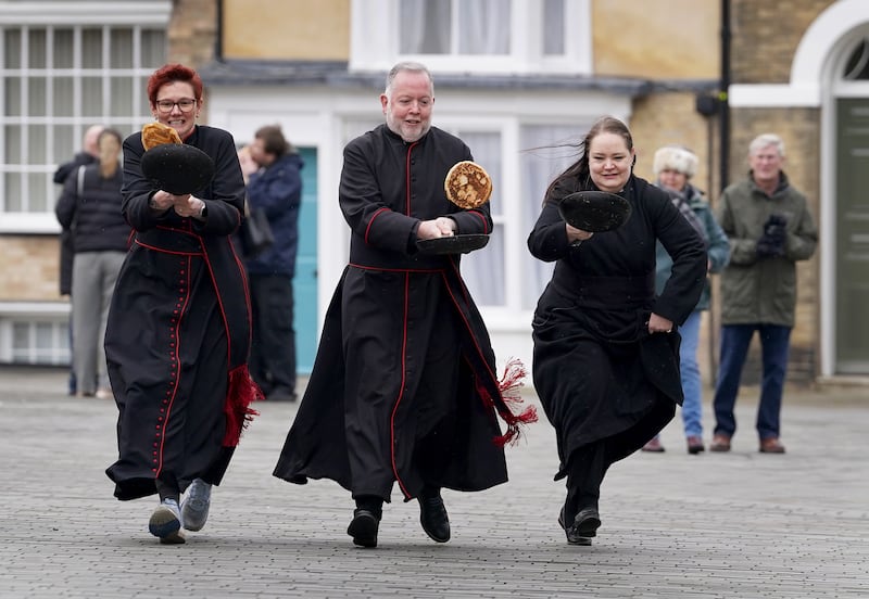 The Very Reverend Dr David Monteith, Dean of Canterbury Cathedral (centre) takes part in a Shrove Tuesday pancake race with members of the clergy at Canterbury Cathedral in Kent