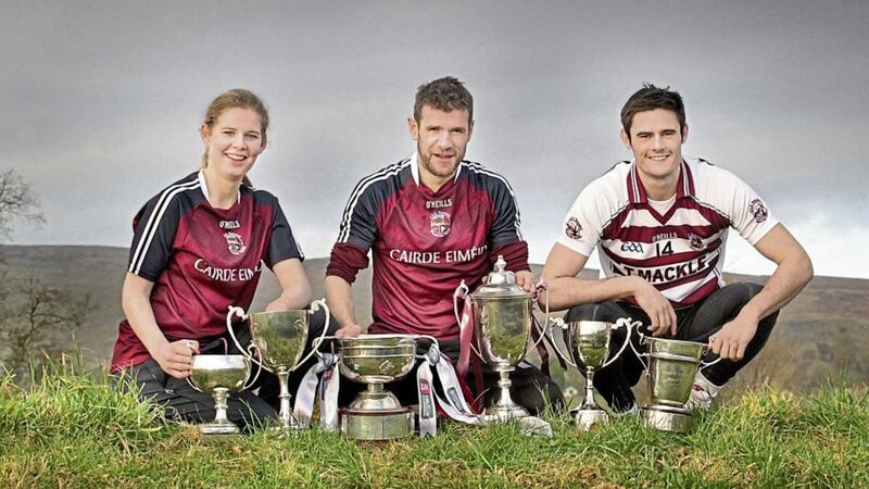 At the foot of Carntogher Mountain, Slaughtneil GAC's historic triple Ulster senior championship captains, Aoife N&iacute; Chaiside, Francis McEldowney and Chrissy McKaigue with their recently collected silverware as Derry and Ulster champions <br />Picture by Margaret McLaughlin