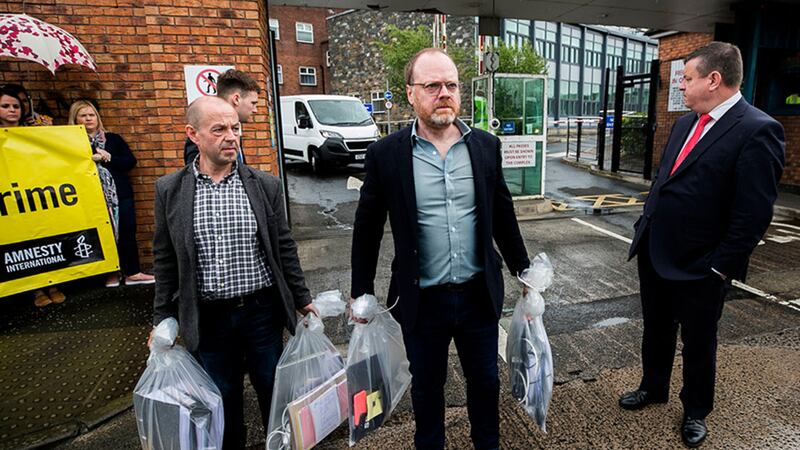 Journalists Barry McCaffrey (left) and Trevor Birney carry some of the materials confiscated as part of the police investigation into their Loughinisland documentary after it was returned this morning&nbsp;