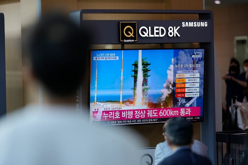 People watch a TV screen showing a news programme about South Korea’s rocket launch at a train station in Seoul 