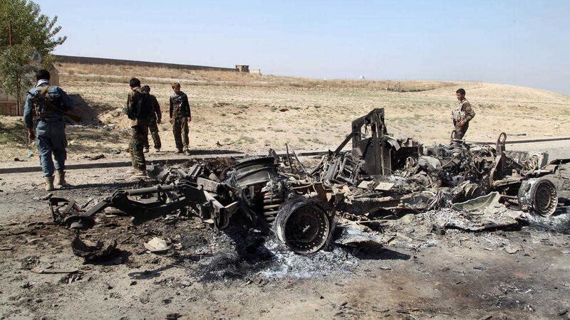 Afghan security personnel walk around a burnt out vehicle near Kunduz city, north of Kabul, Afghanistan. Picture by AP