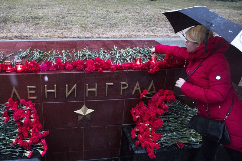 a woman lights a candle in memory of the victims (Pavel Golovkin/AP)
