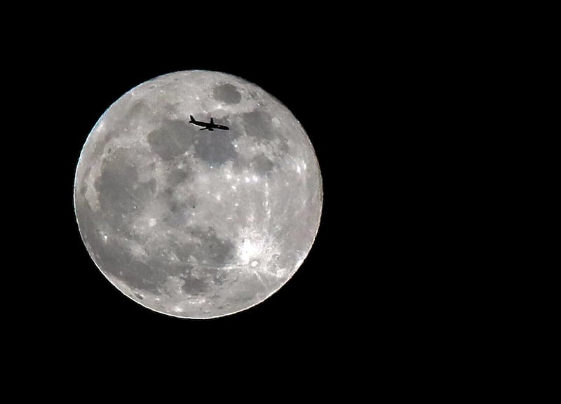 Giant moon silhouetted by passenger jet
