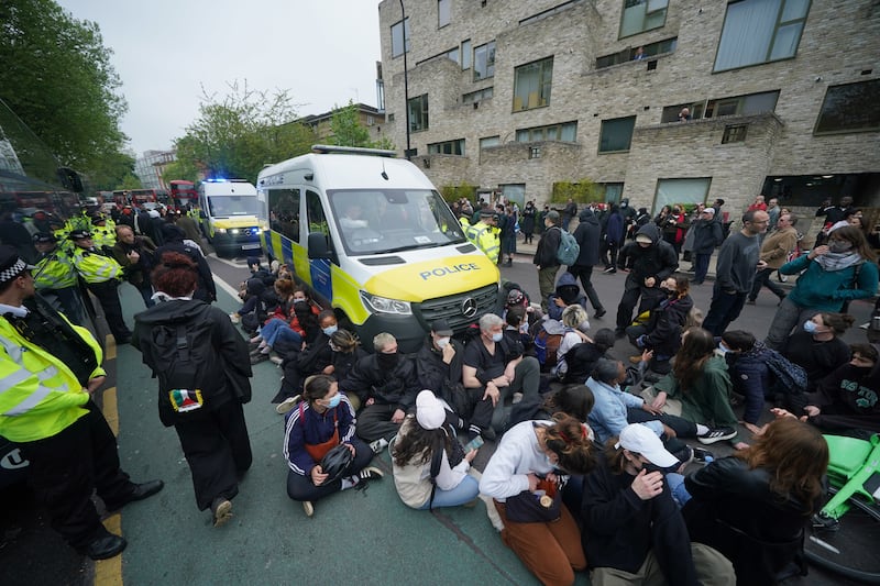 Protesters sat in front of a police van after forming a blockade around the coach