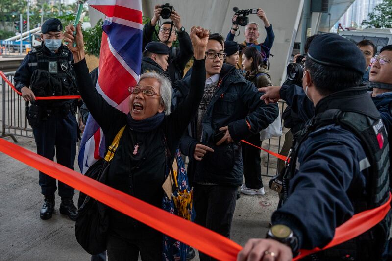 Activist Alexandra Wong holding a British flag shouts behind a police line set up outside West Kowloon Magistrates’ Court (AP)