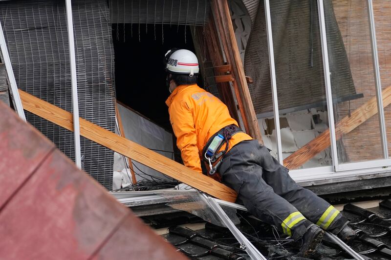 A rescue worker searches a collapsed house caused by a powerful earthquake in Suzu, Ishikawa Prefecture (Hiro Komae/AP)