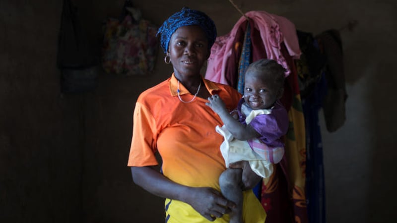 Sore Habibou (33) holds her two-year-old daughter, Rihana, in her home in Louda village, Burkina Faso  