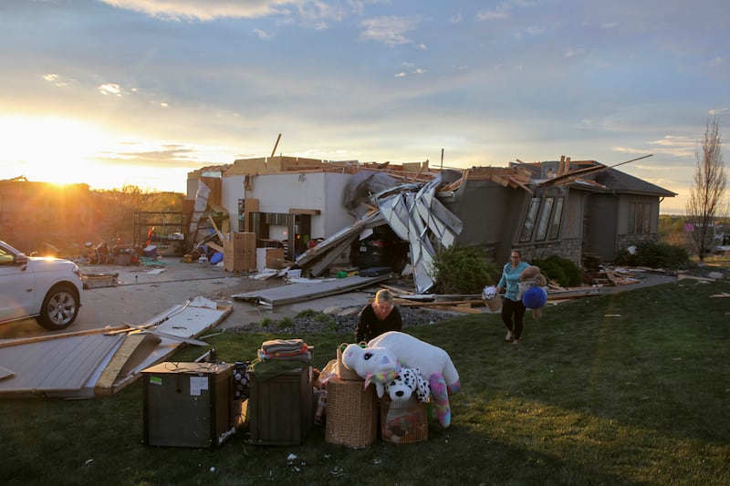 Two women help carry a friend’s belongings out of their damaged home after a tornado passed through the area in Nebraska (Josh Funk/AP)