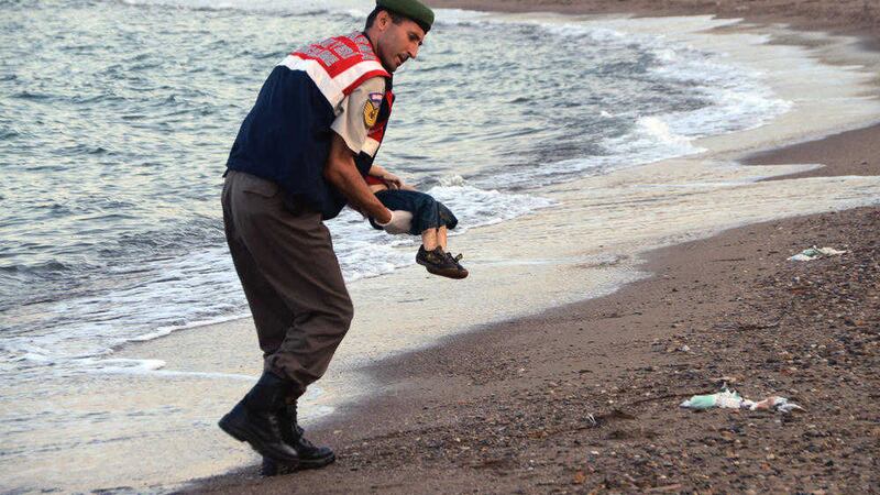 A paramilitary police officer carries the lifeless body of Alan Kurdi, 3, off a Turkish beach last year 