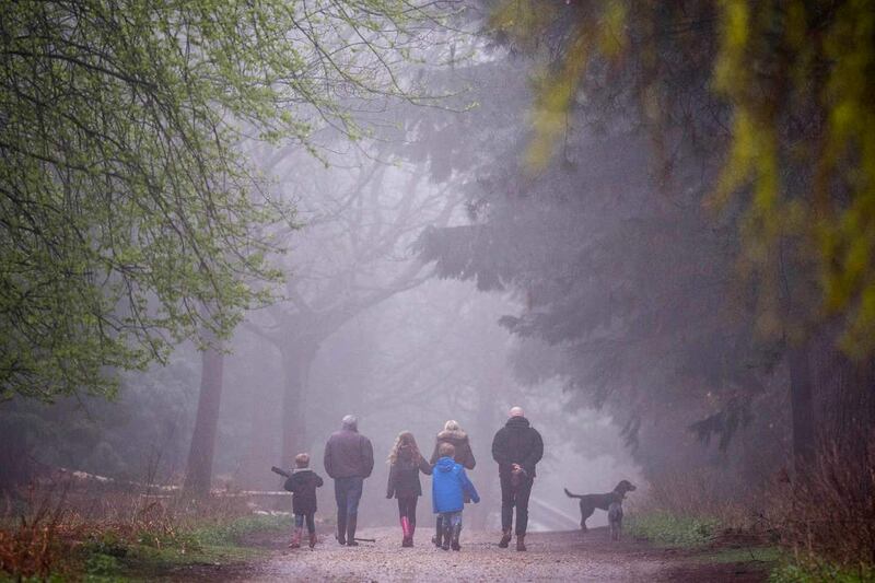A family walk through the mist in Epping Forest, London, as the wet weather is set to give way to warm sunshine (Victoria Jones/PA)