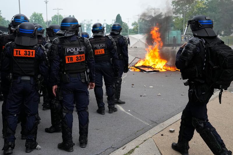 Riot police officers stand by a fire after a march for Nahel in Nanterre
