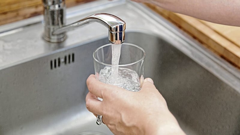 woman holding glass at water tap and filling water.. 