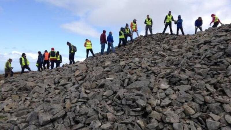 Volunteers climb to the summit of Slieve Gullion to begin repair work to a burial tomb. Picture from BBC 