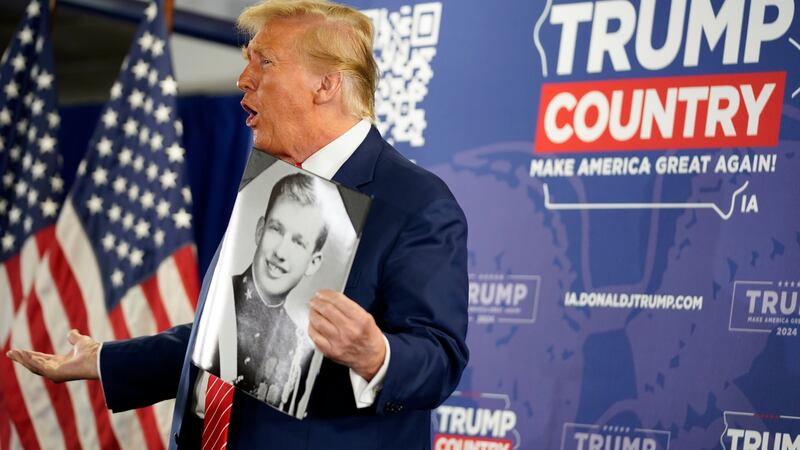 Donald Trump holds a military academy photo of himself that he got from a person in the crowd (AP)