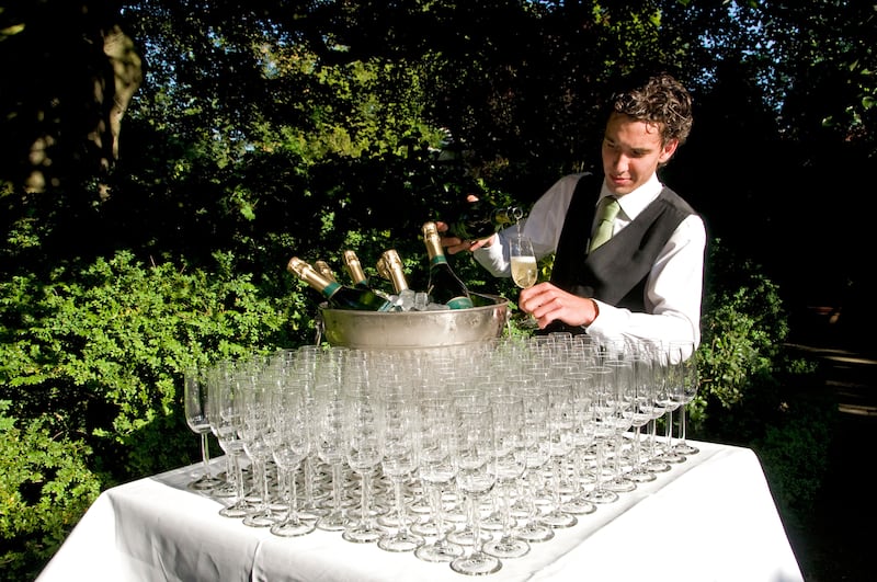 Champagne flutes at a wedding reception with waiter serving drinks