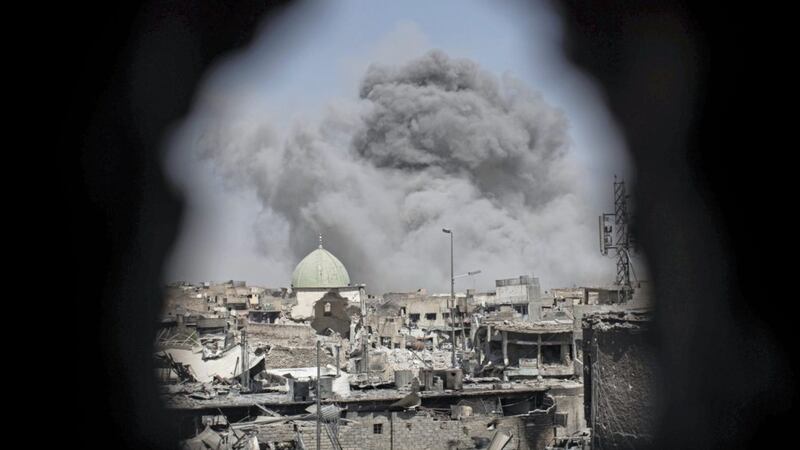 A bomb explodes behind the al-Nuri mosque complex, as seen through a hole in the wall of a house, as Iraqi Special Forces move toward Islamic State militant positions in the Old City of Mosul, Iraq, on Thursday. Picture by Felipe Dana, Associated Press 