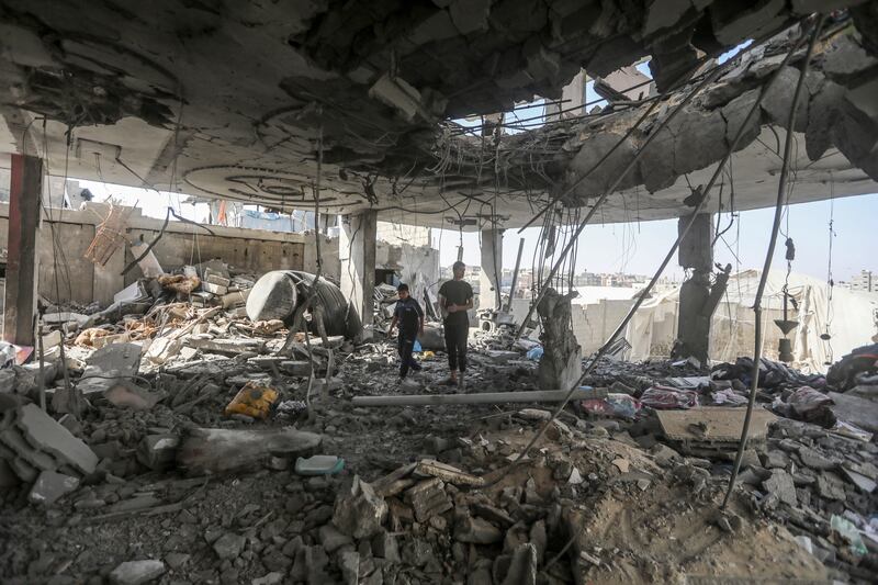 Palestinians stand in the ruins of a family home, after an overnight Israeli strike (Ismael Abu Dayyah/AP)