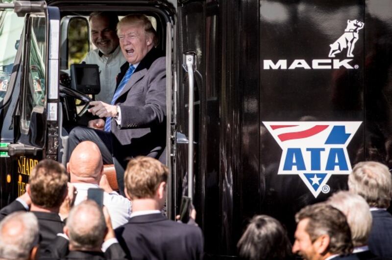 President Donald Trump jokes as he sits in the drivers seat of an 18-wheeler