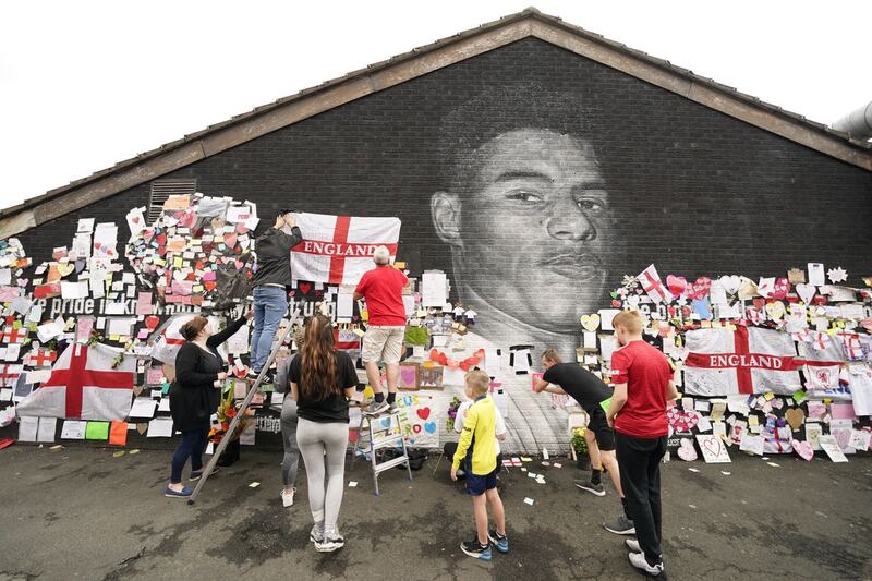 People put up flags and messages on the mural of Manchester United striker and England player Marcus Rashford on the wall of the Coffee House Cafe on Copson Street, Withington, after it had been defaced