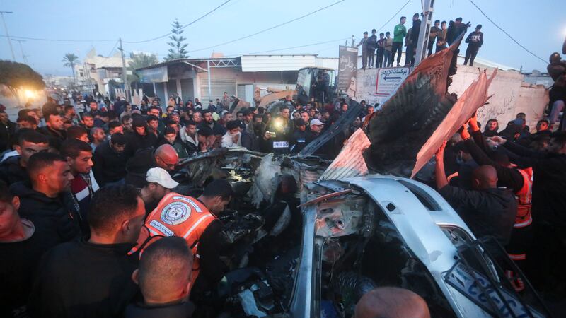Palestinians surround a car hit by an Israeli air strike in Rafah, Gaza (Hatem Ali/AP)