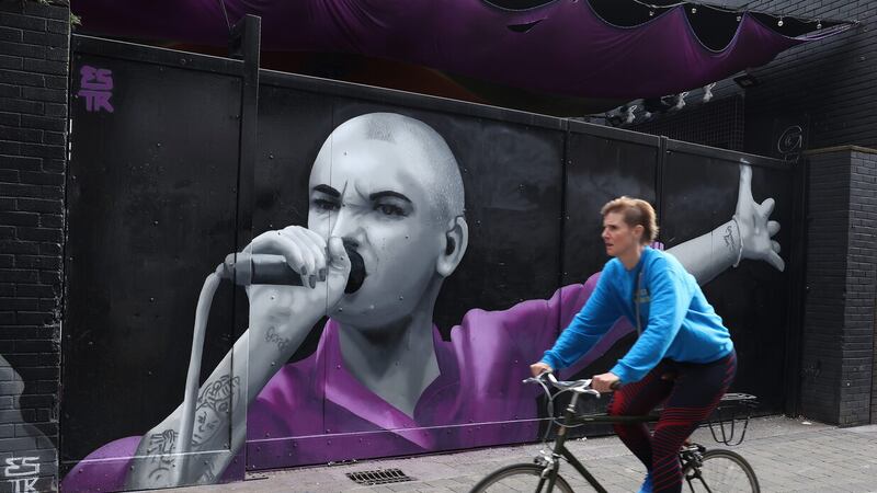 A cyclist passes a mural of Sinead O'Connor by Artist, Emmalene Blake on Dame Lane in Dublin. (Damien Eagers/PA Wire)